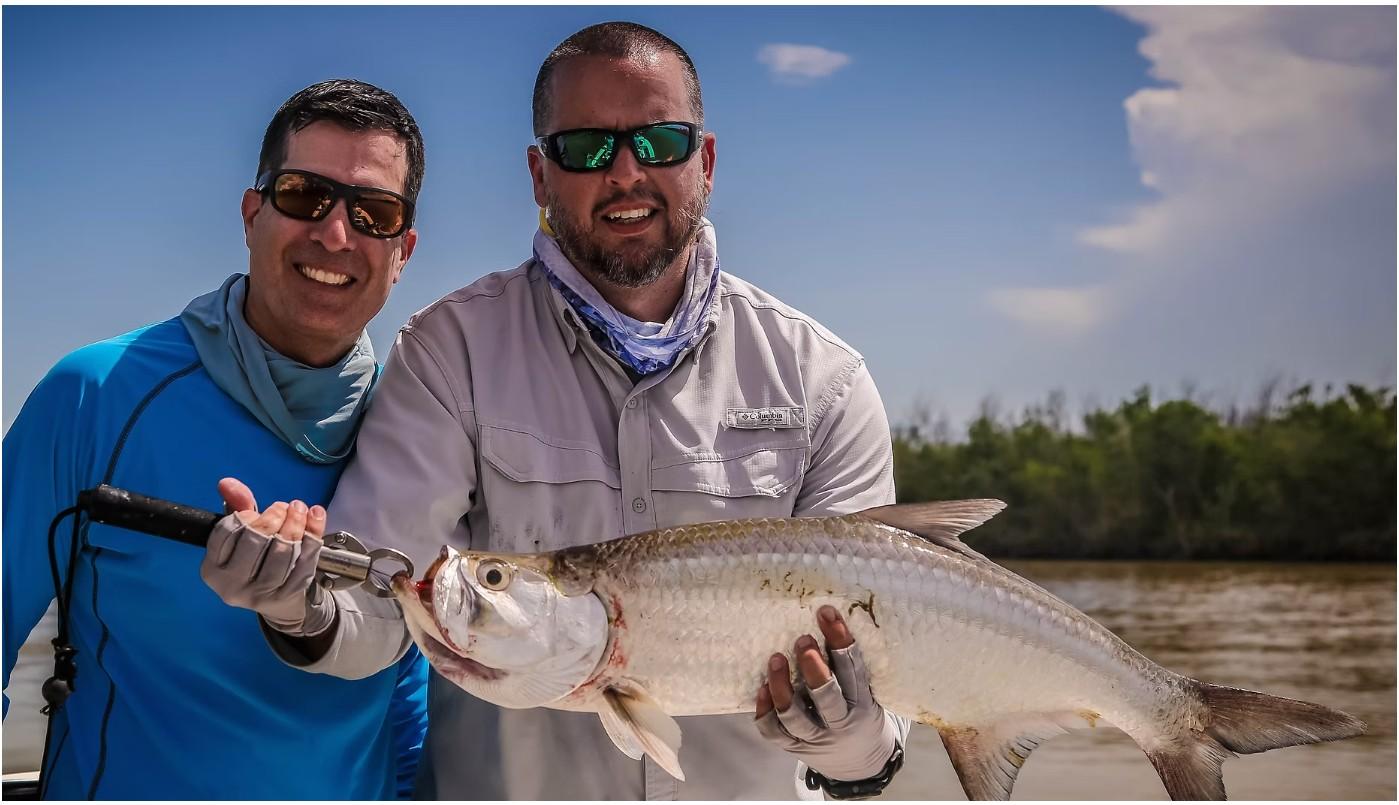 Captain Armando Alejo holding a tarpon on an A2 Fishing Charters trip